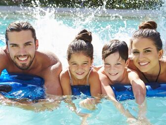 Family resting on a raft in a pool smiling